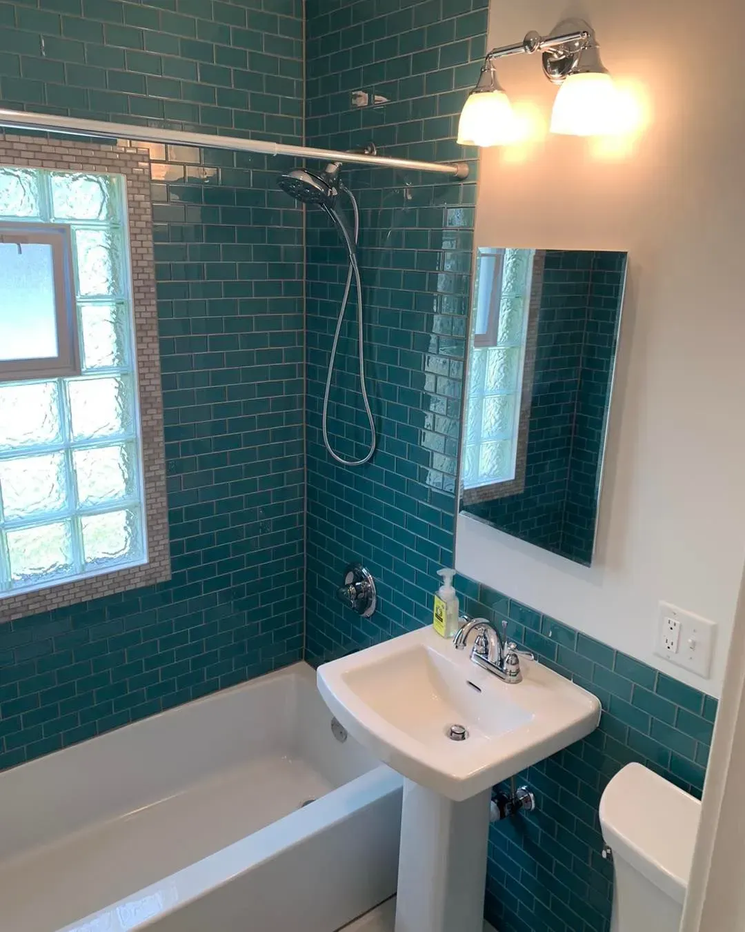 A bathroom with a sink , tub , toilet and mirror.