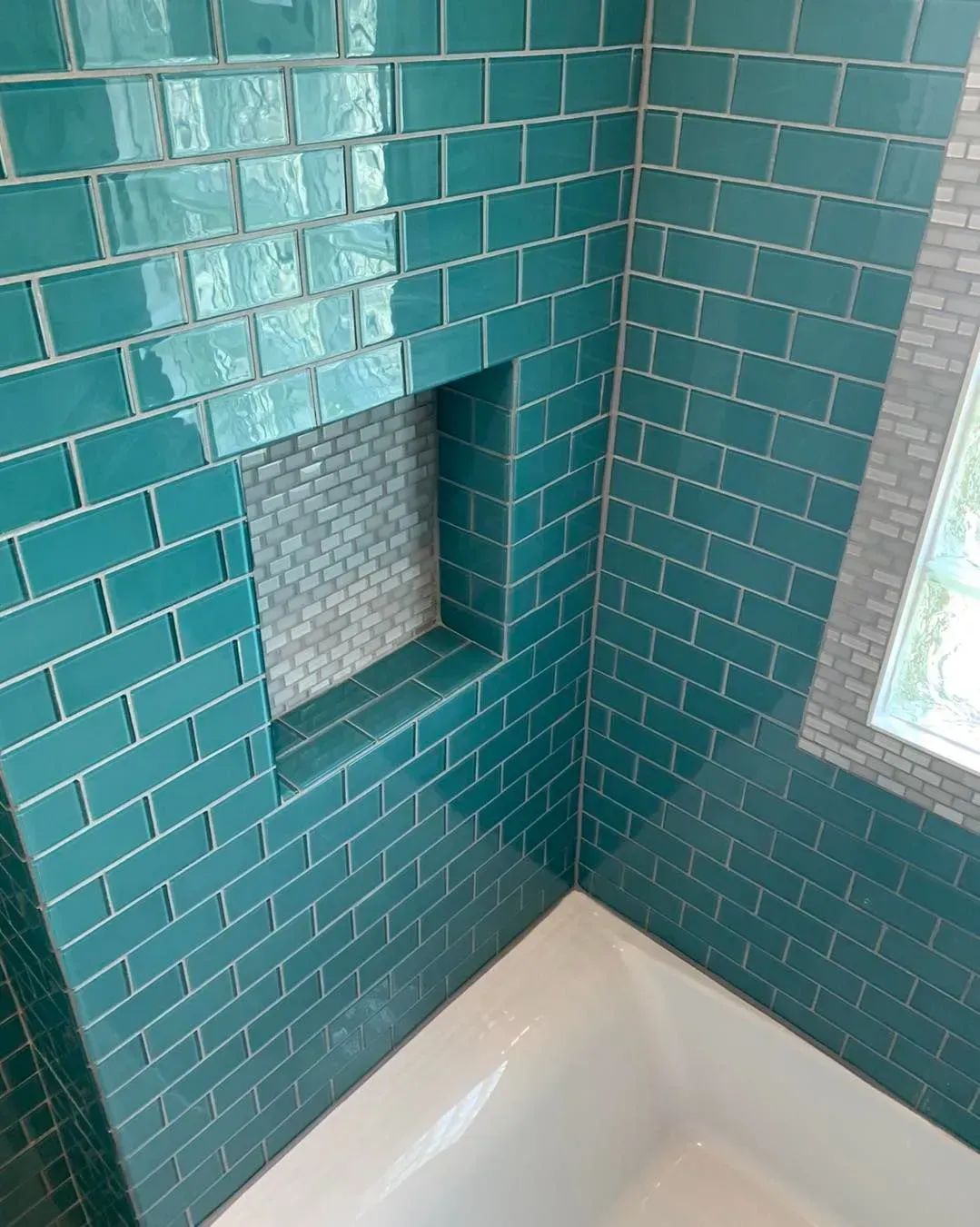 A bathroom with blue tiles and a window.