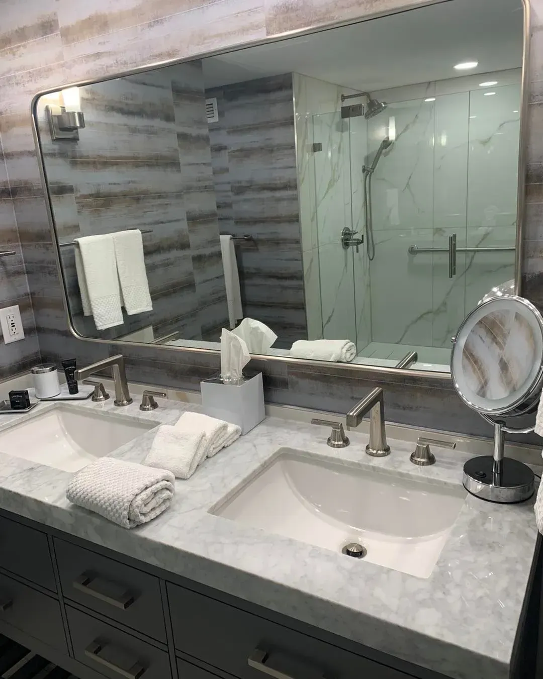 A bathroom with two sinks , a mirror and a shower.