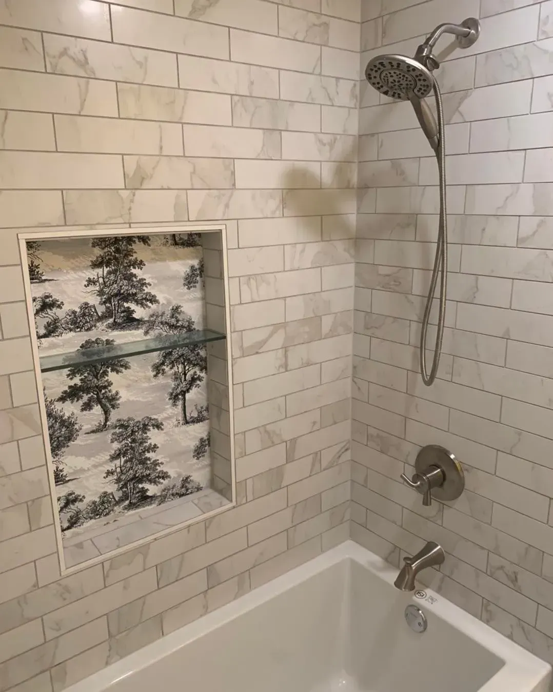 There is a bathtub in the shower with a shower head.