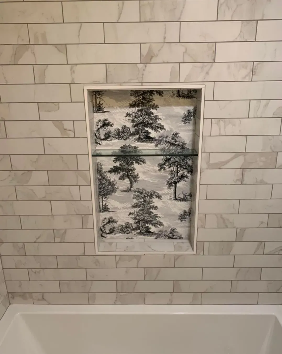 There is a shelf in the wall next to the bathtub.