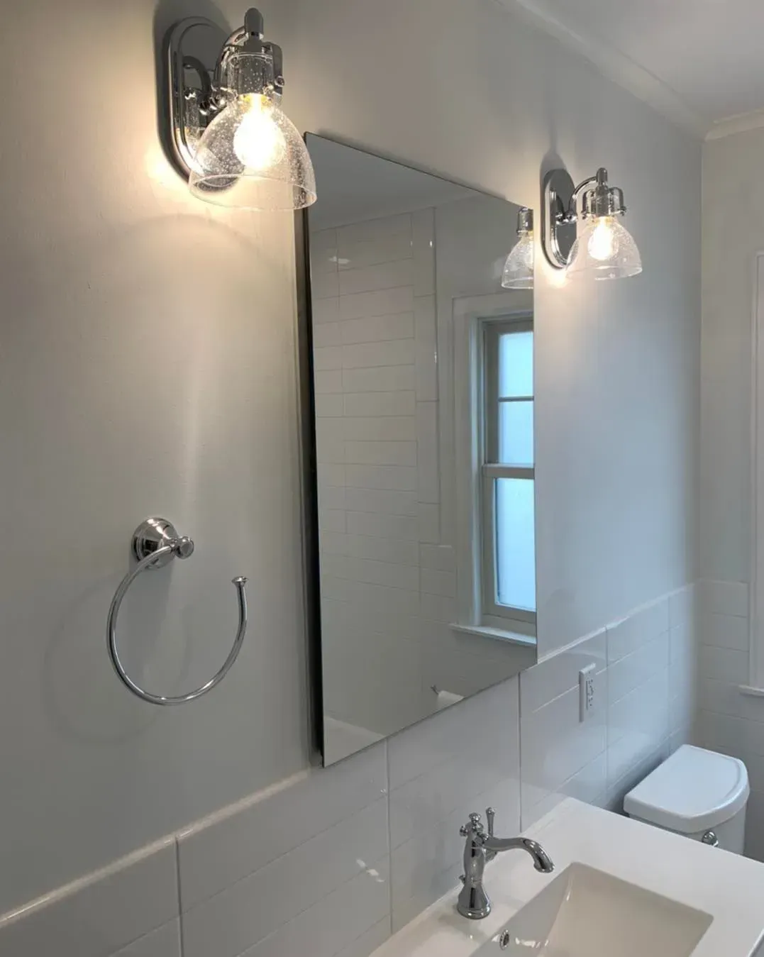 A bathroom with a sink , toilet and mirror.