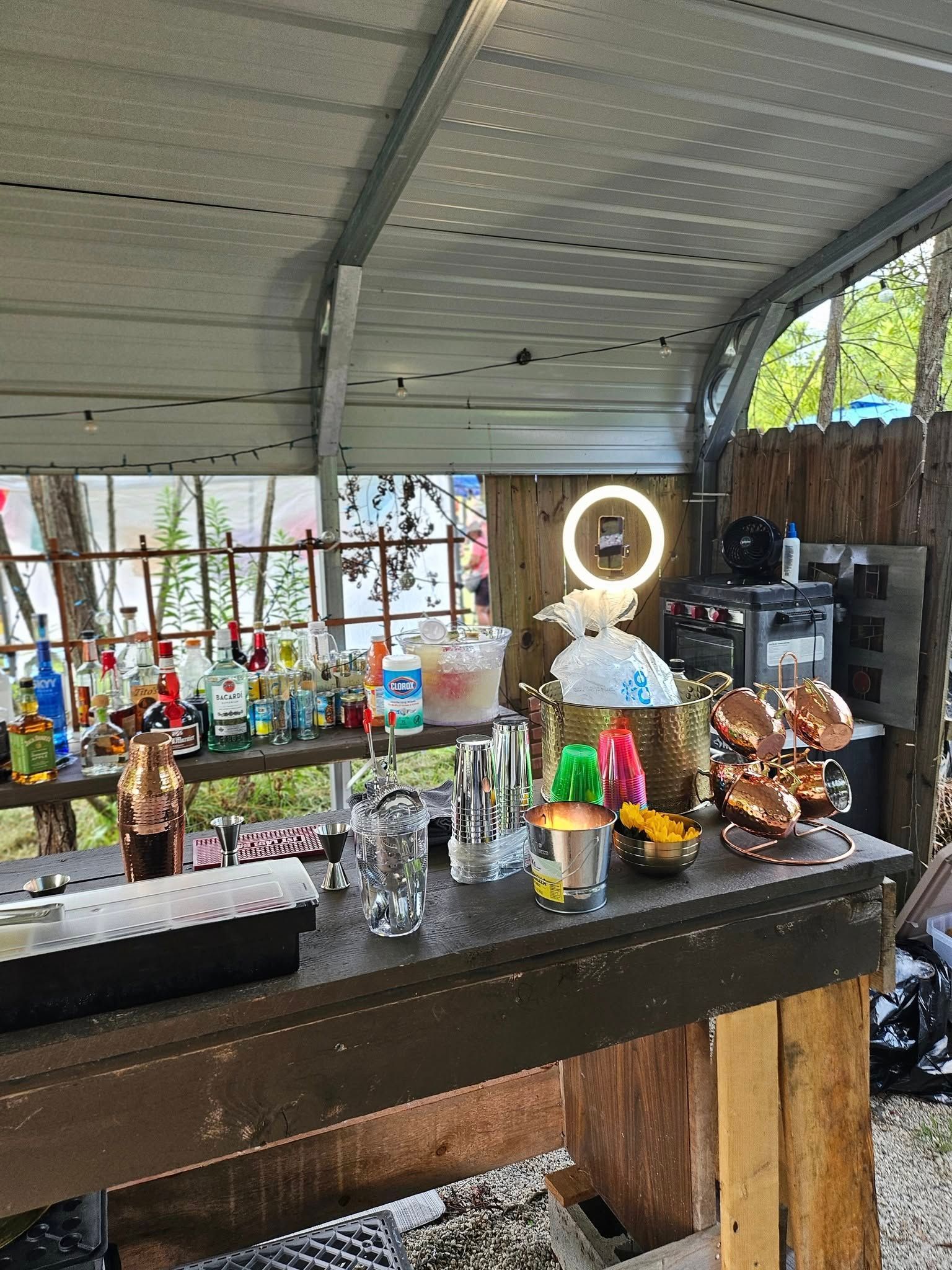A wooden table with a lot of bottles and glasses on it.