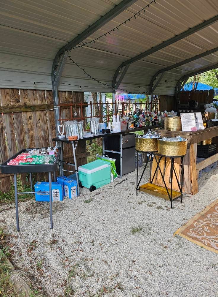 A covered area with tables , coolers , pots and pans.