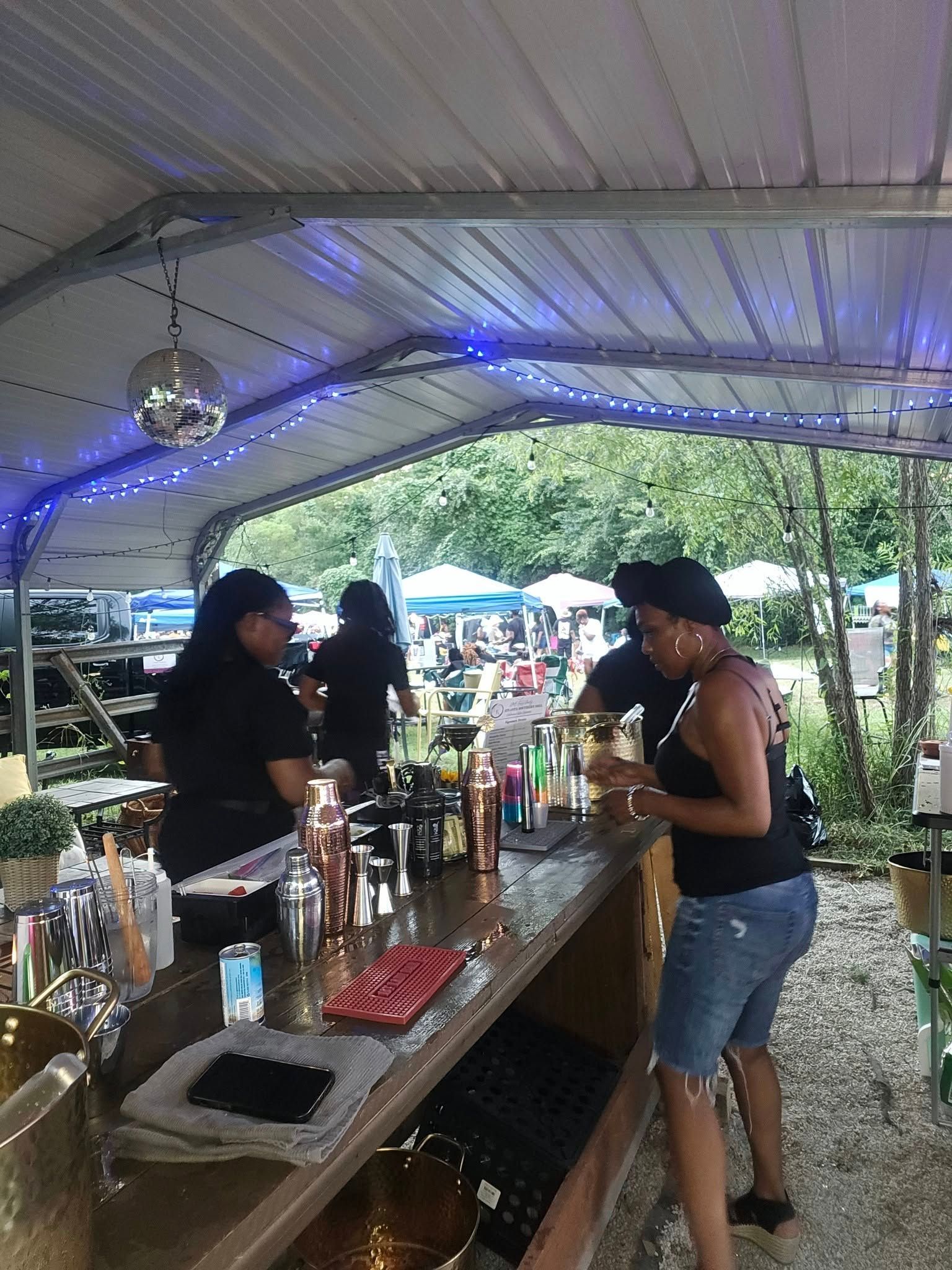 A woman is standing at a bar preparing drinks.
