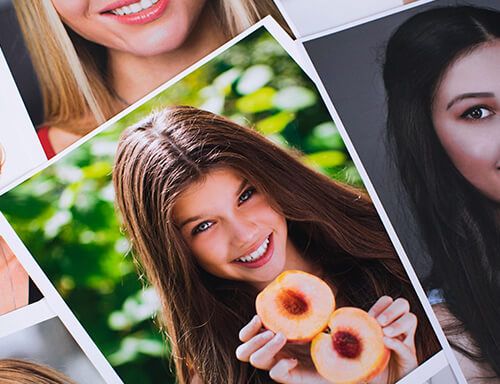 A woman is holding two peaches in her hands and smiling.