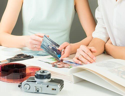Two people are sitting at a table looking at a photo album.