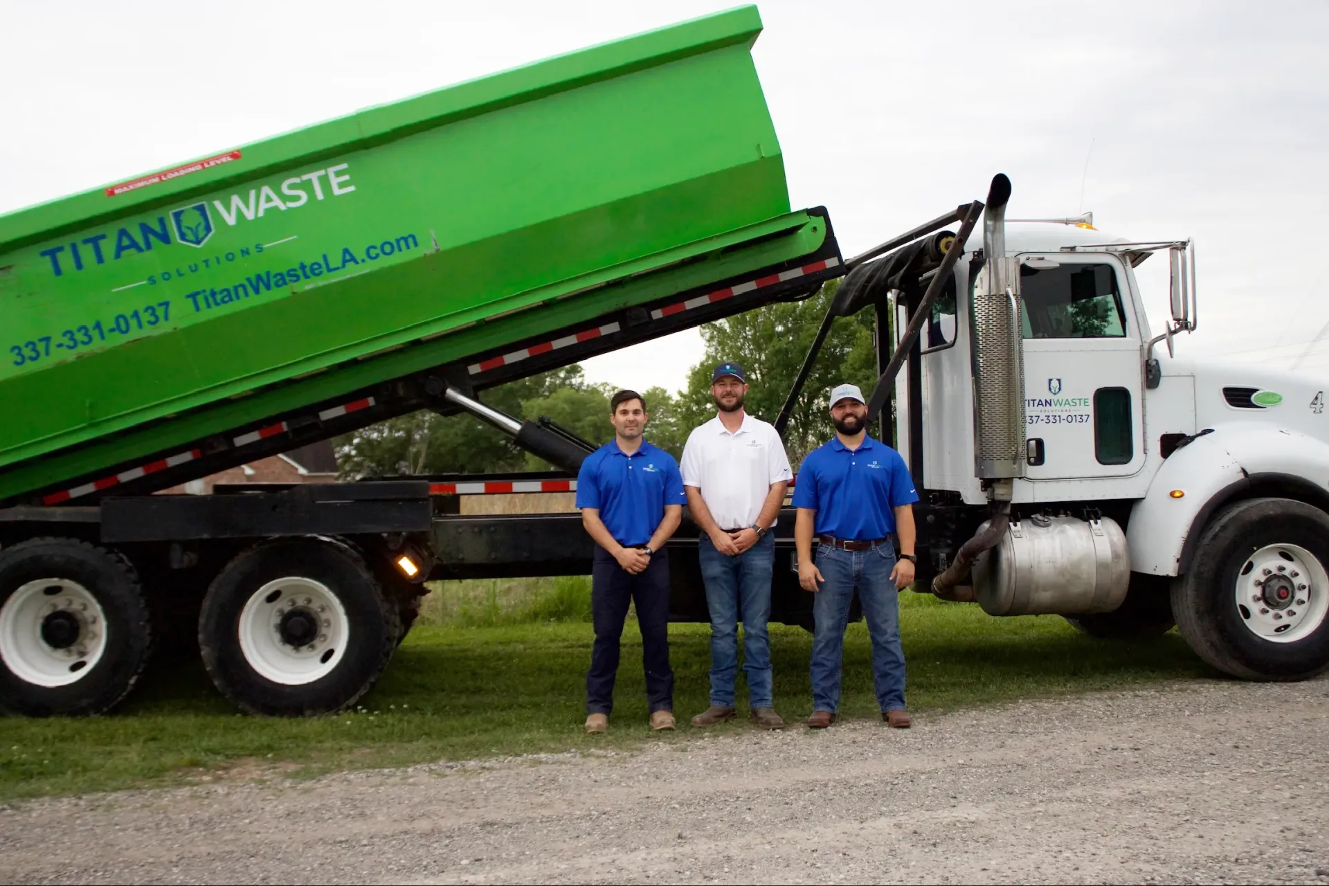 Three men are standing in front of a dump truck.