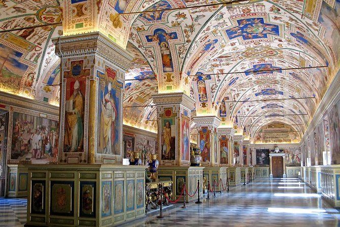 A long hallway with columns and paintings on the ceiling.