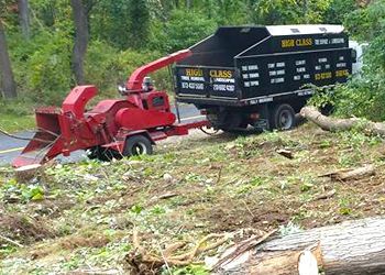 A tree chipper is pulling a dumpster on a trailer.