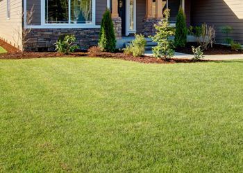 A house with a lush green lawn in front of it.