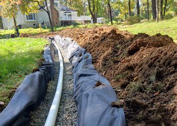 A drainage system is being installed in the backyard of a house.