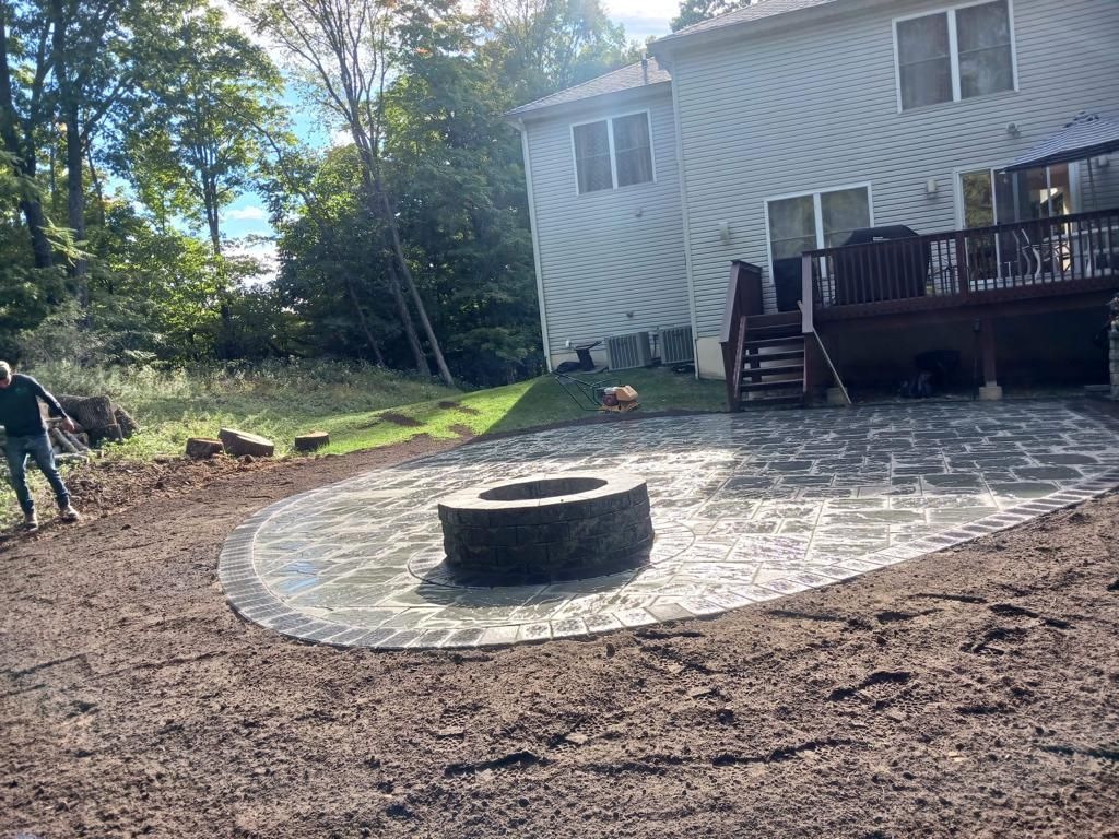 A fire pit is in the middle of a patio in front of a house.