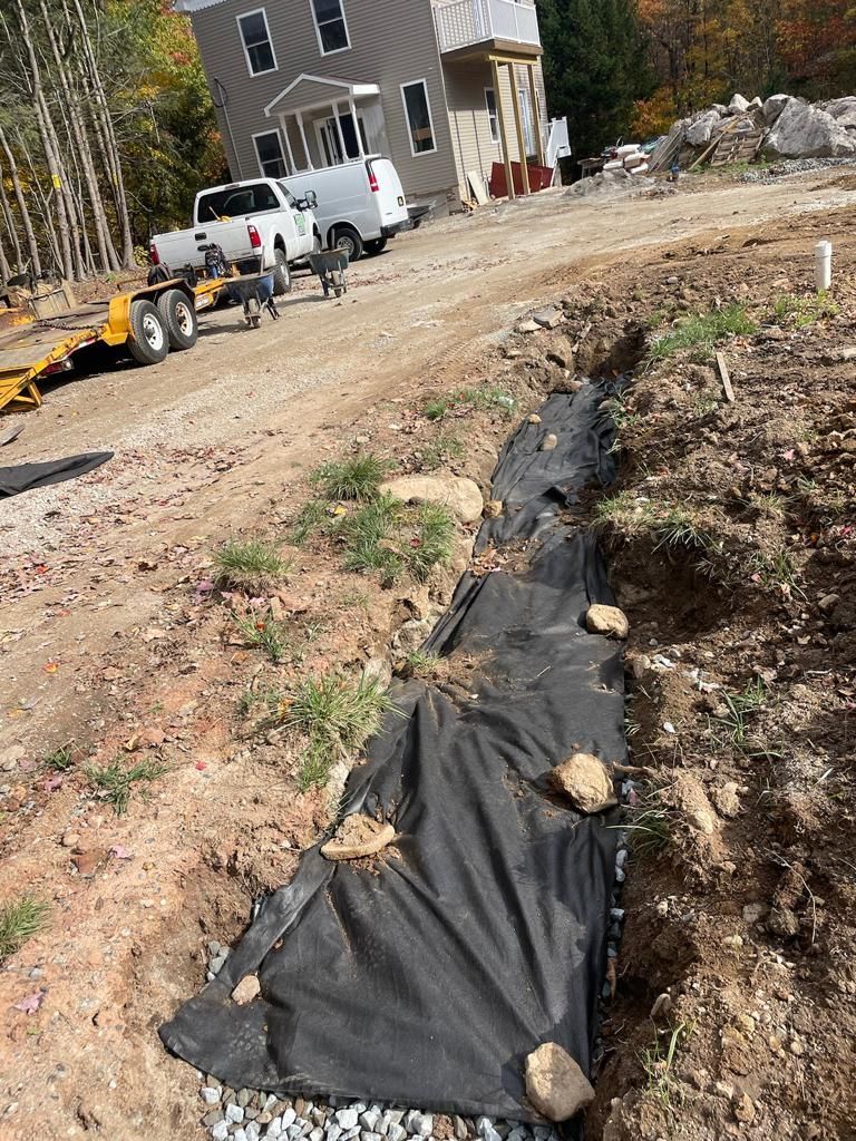 A truck is parked on the side of a dirt road next to a house.