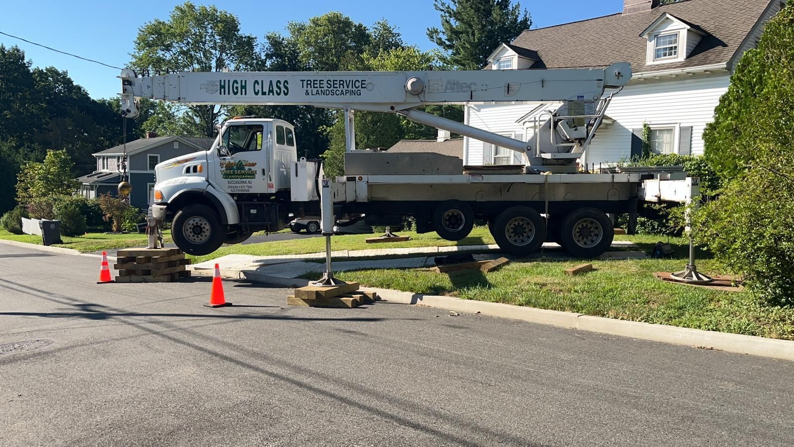 A crane truck is parked on the side of the road in front of a house.