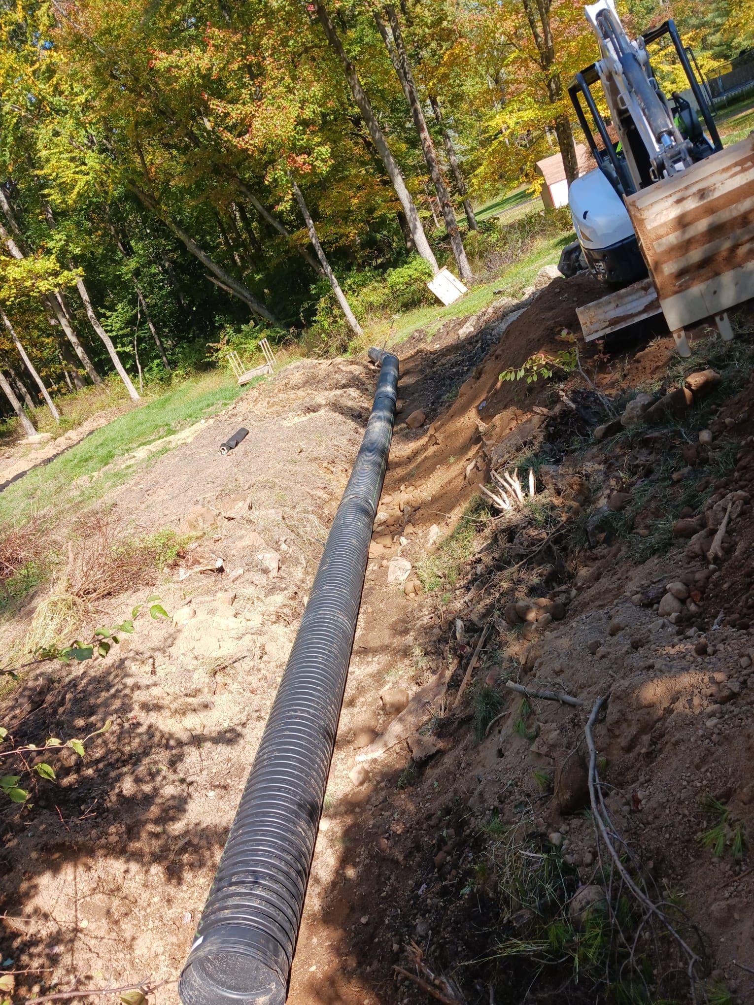 A large pipe is sitting in the dirt next to a bulldozer.