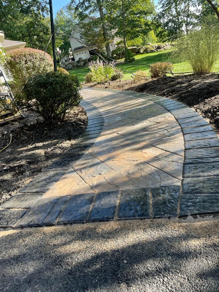 A stone walkway leading to a house in a park.