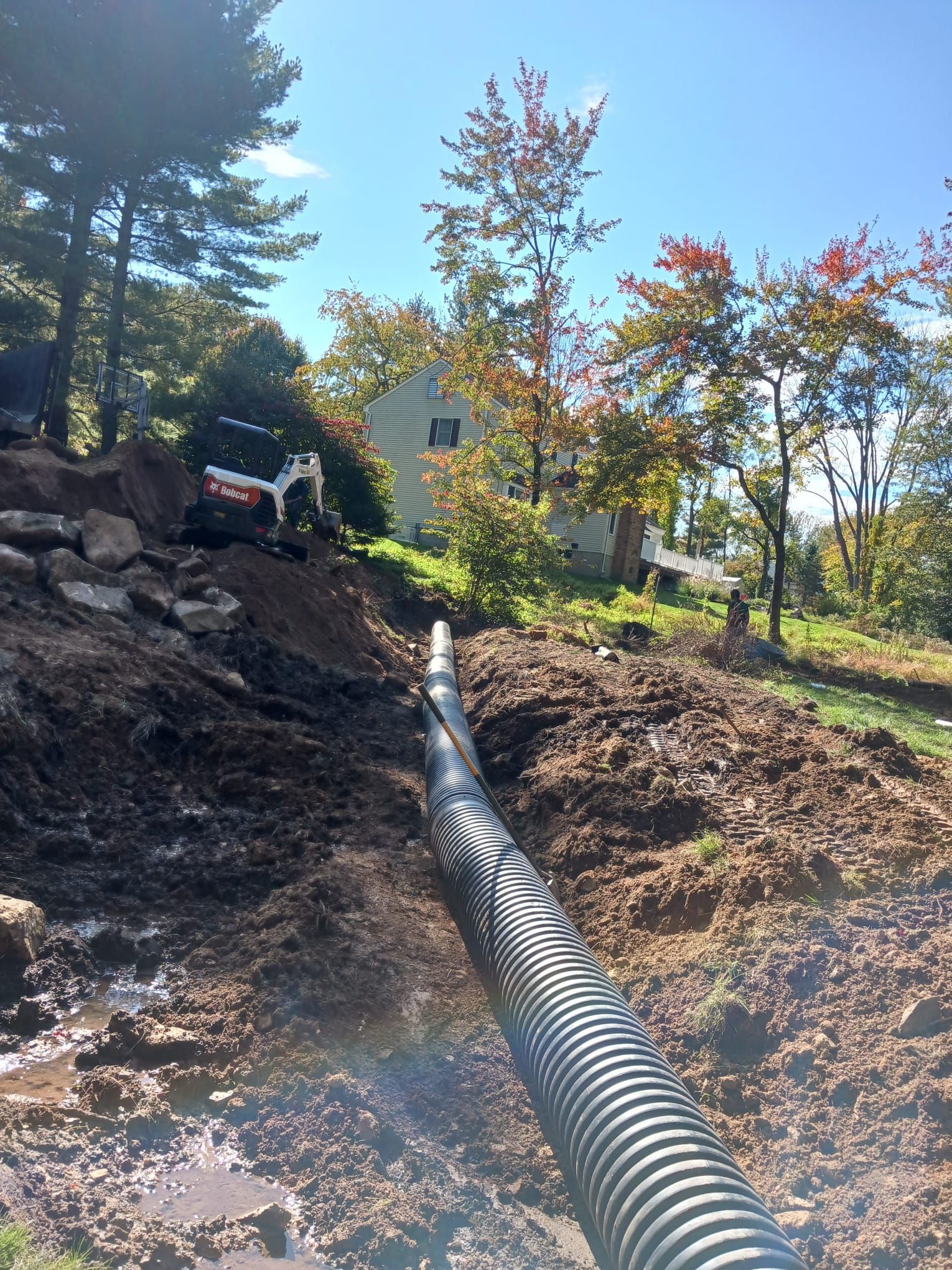 A hose is being installed in a muddy area in front of a house.