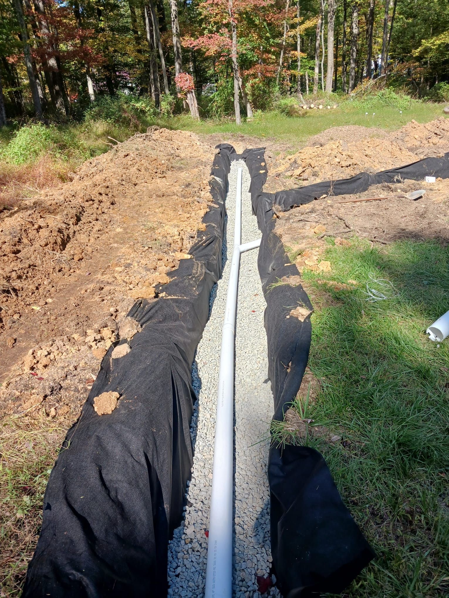 A white pipe is sitting in the middle of a dirt field.