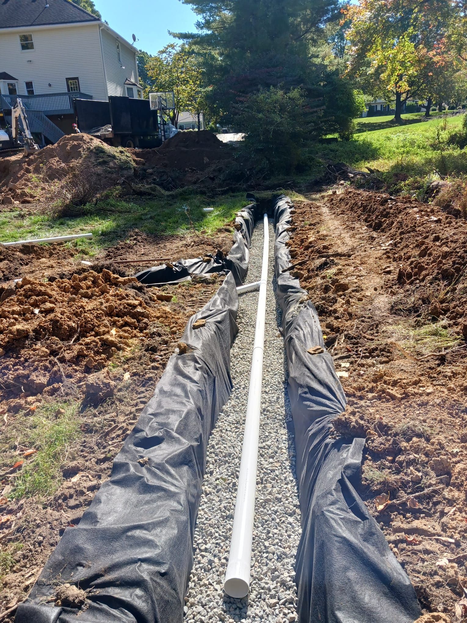 A pipe is being installed in the dirt in a yard.