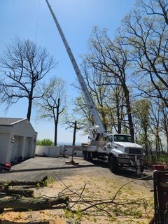 A white truck with a crane attached to it is parked in front of a house.
