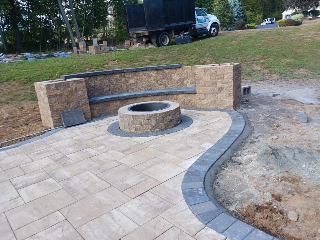 A fire pit is sitting on top of a patio next to a brick wall.