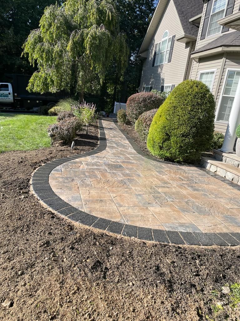 A walkway leading to a house with a car parked in front of it.