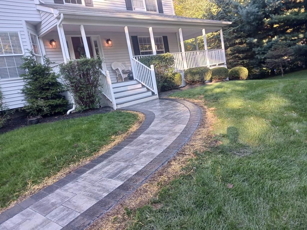 A walkway leading to a house with a porch and stairs.