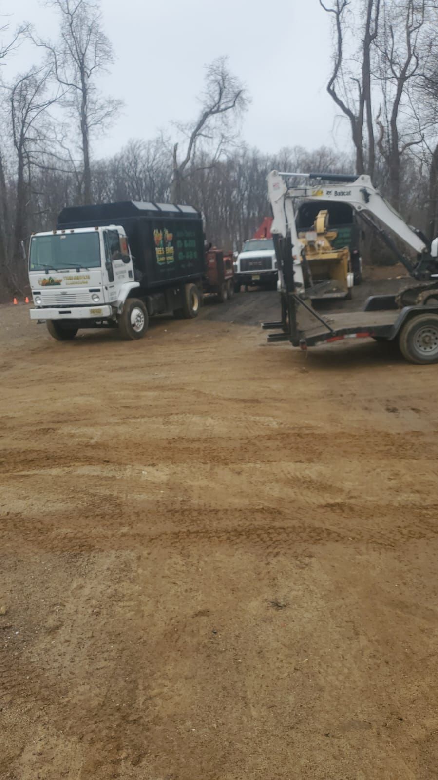 A dump truck and an excavator are parked in a dirt lot.