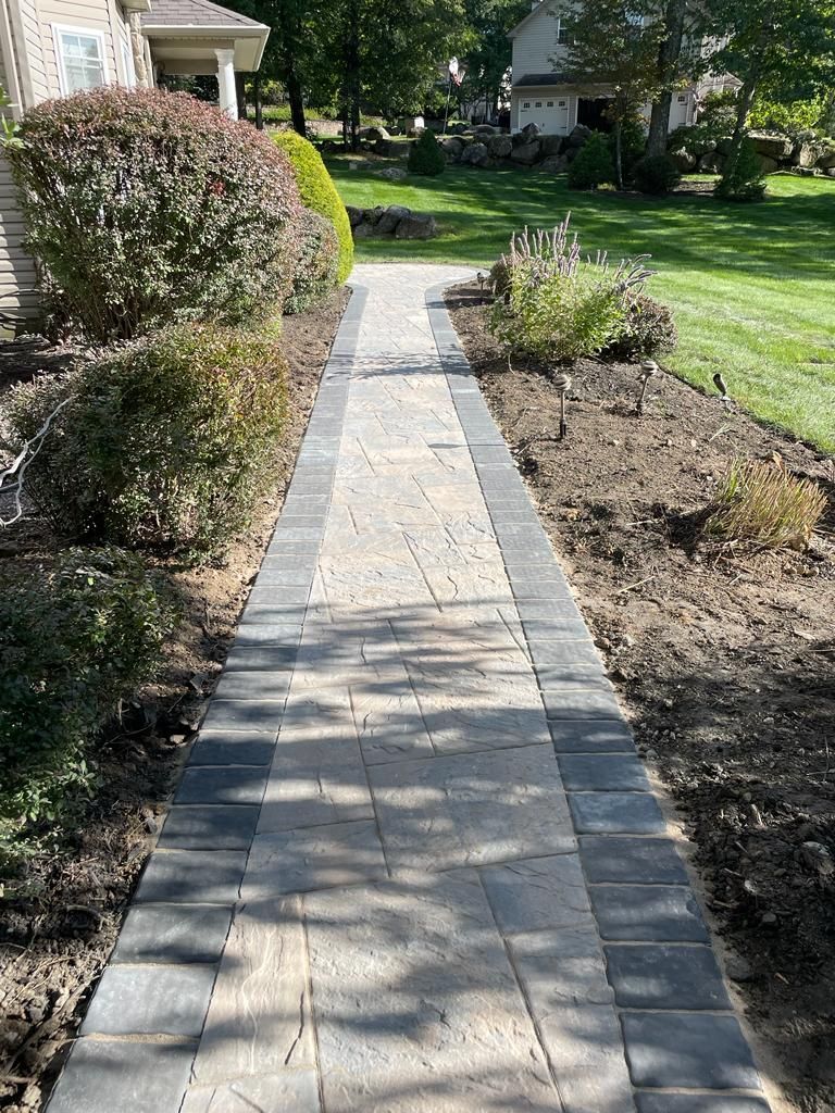 A brick walkway leading to a house in a residential area.