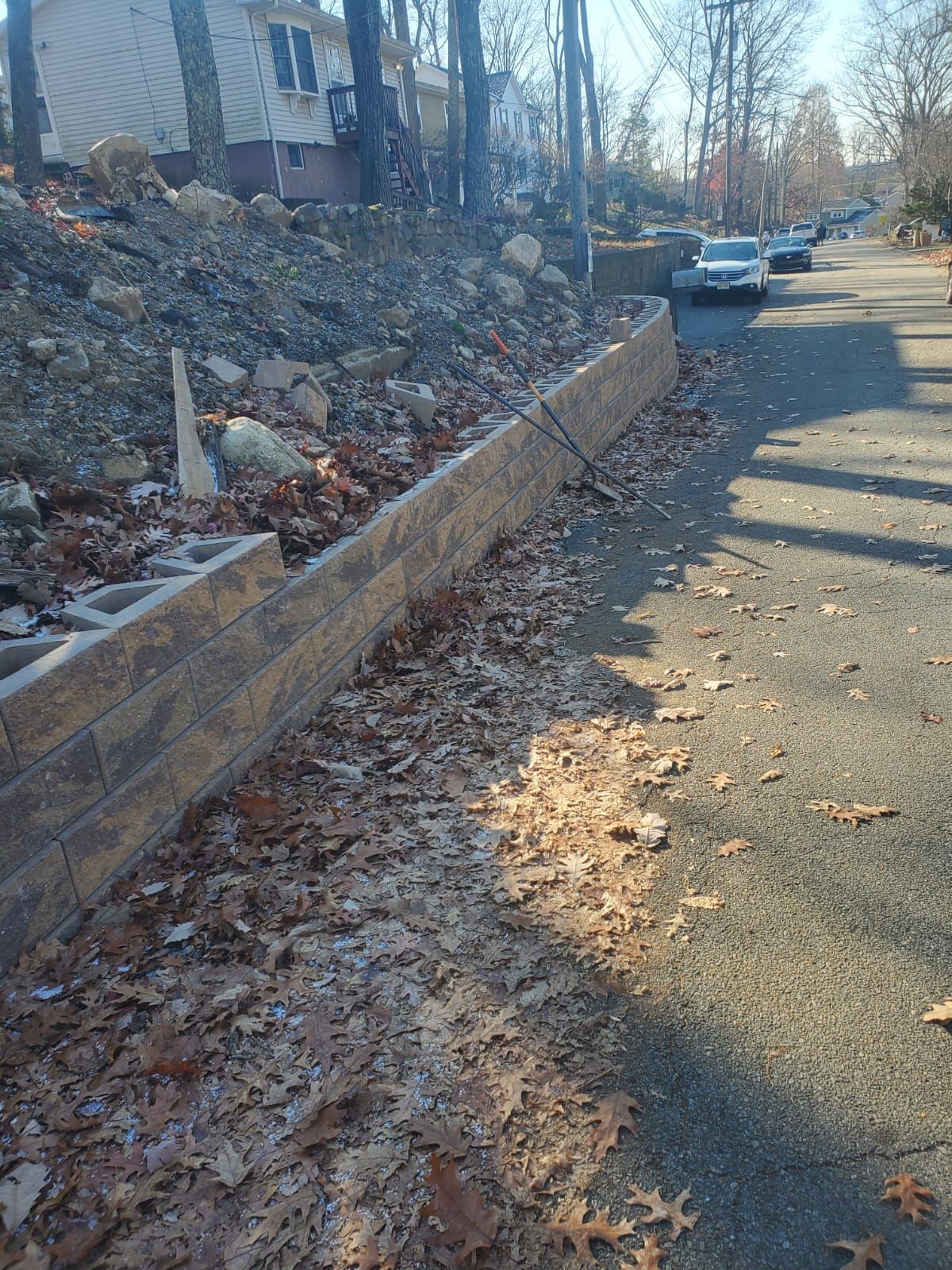 A brick wall is being built on the side of a road.