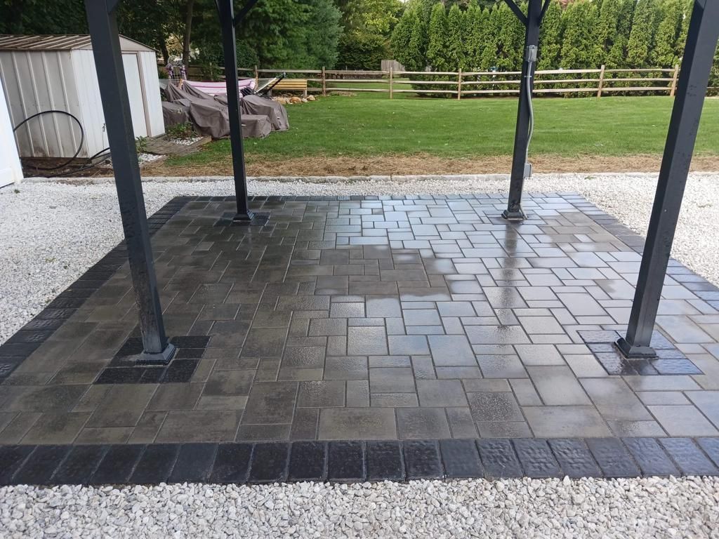 A patio with a pergola and a fence in the background.