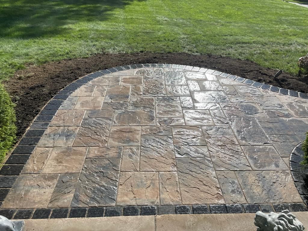 A stone walkway leading to a lush green lawn.