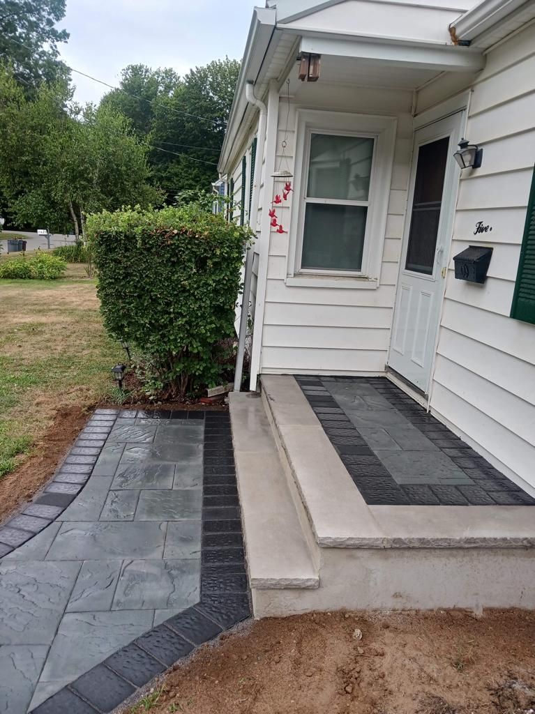 A white house with a brick walkway leading to the front door.