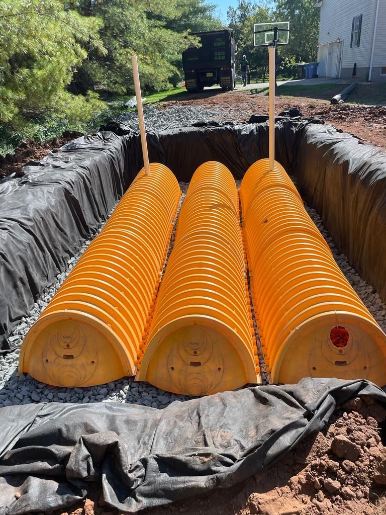 Three yellow barrels are sitting in a hole in the ground.