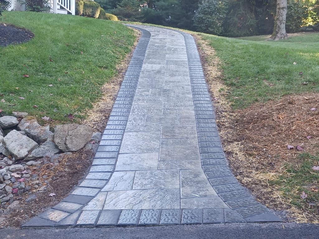 A brick walkway leading to a house on a hill.