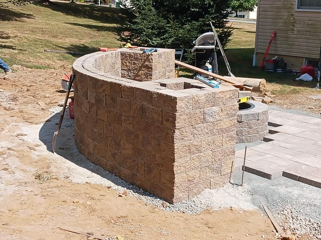 A brick wall is being built in the dirt in front of a house