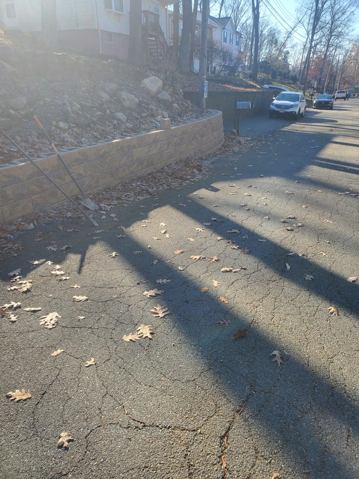 A shadow of a car is cast on the side of a road.