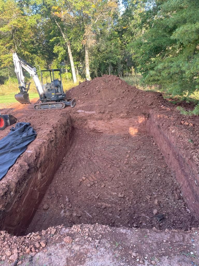 A bulldozer is digging a hole in the ground next to a pile of dirt.