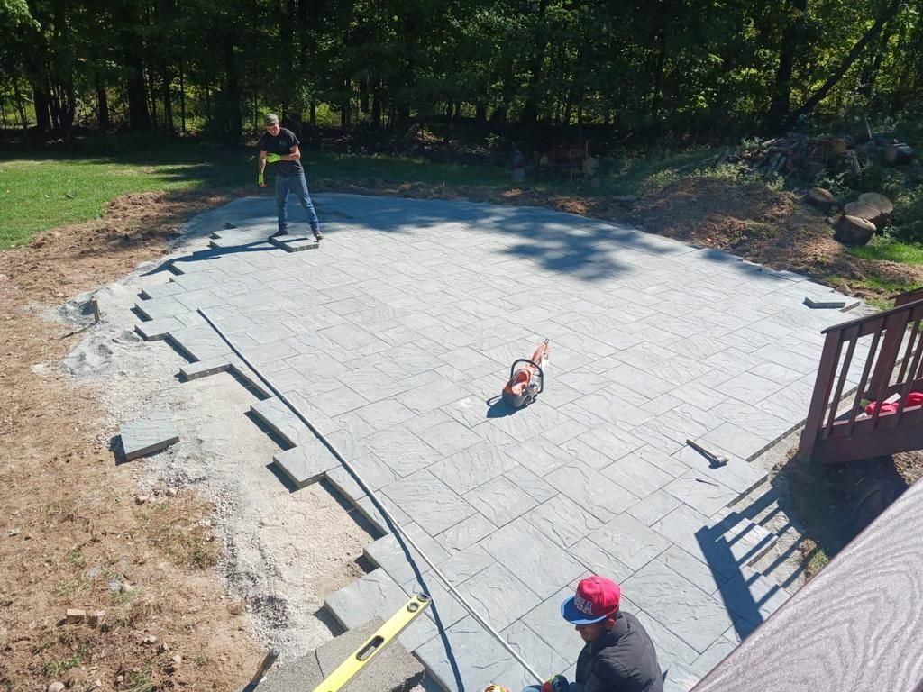 A man and a dog are working on a patio.