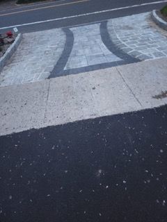 A black and white photo of a sidewalk next to a road.