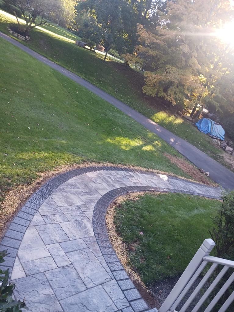 A curved walkway leading to a grassy hillside.