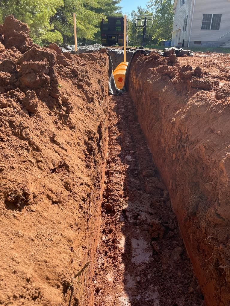 A trench is being dug in the dirt in front of a house.