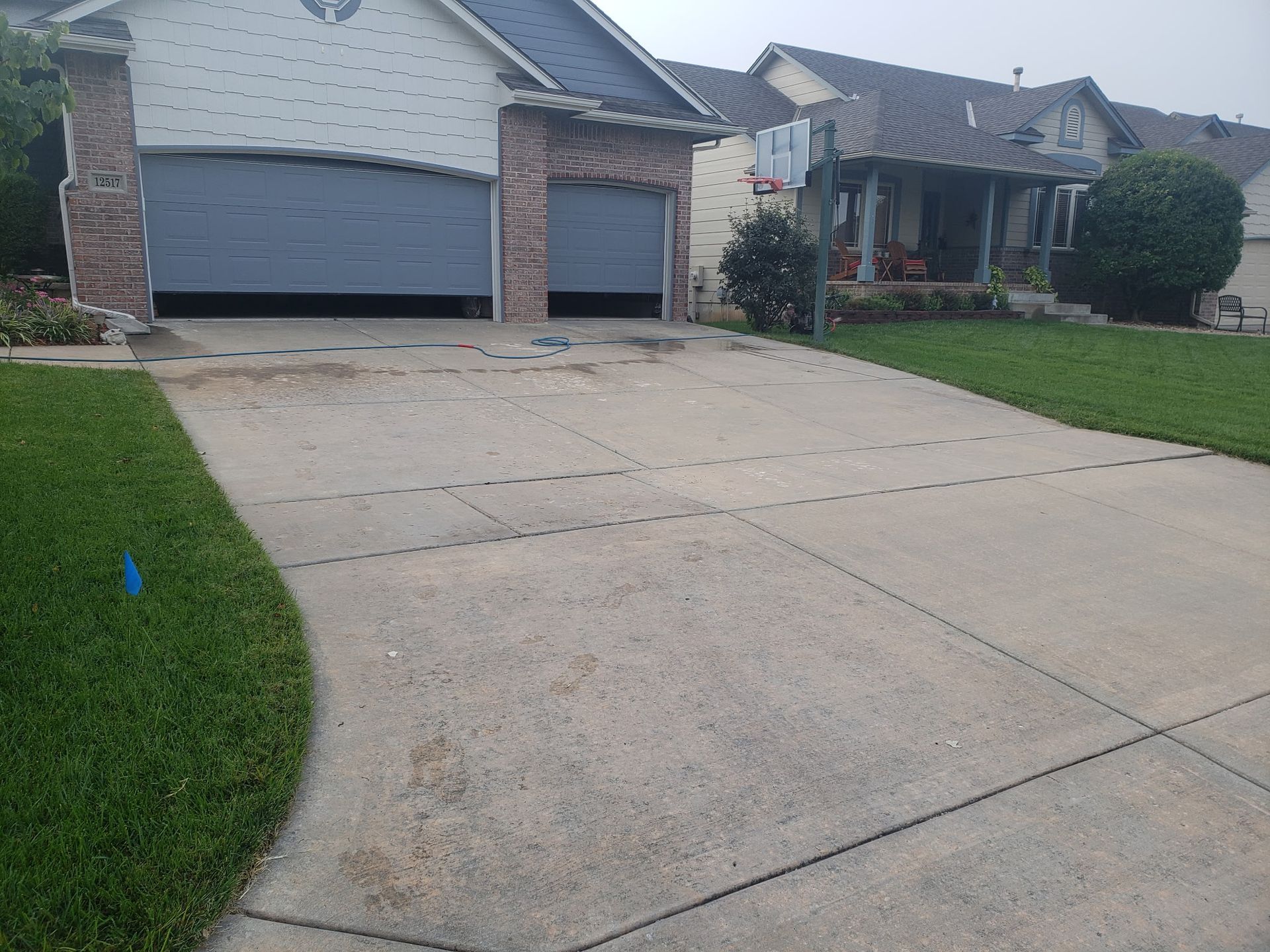 A concrete driveway leading to a house with two garage doors.