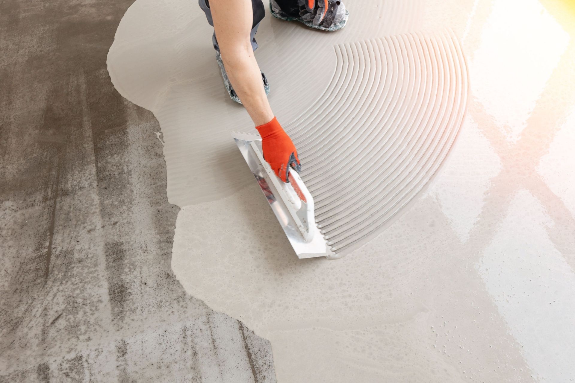 A person is plastering a floor with a trowel.