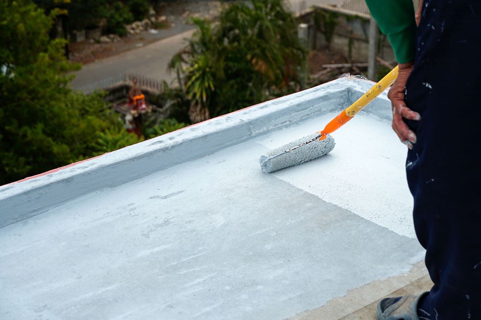 A person is painting a roof with a roller.