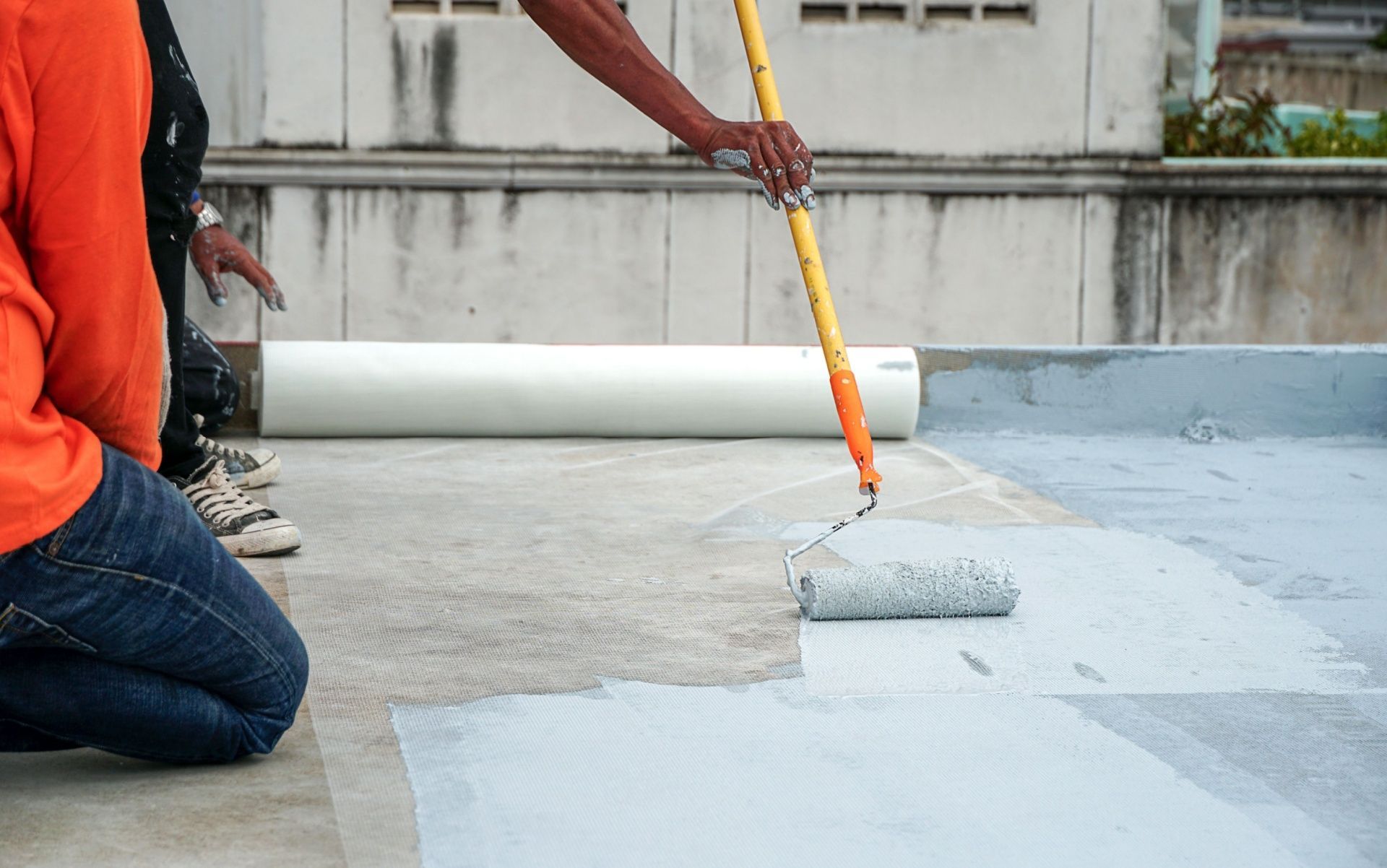A man is painting a roof with a roller.