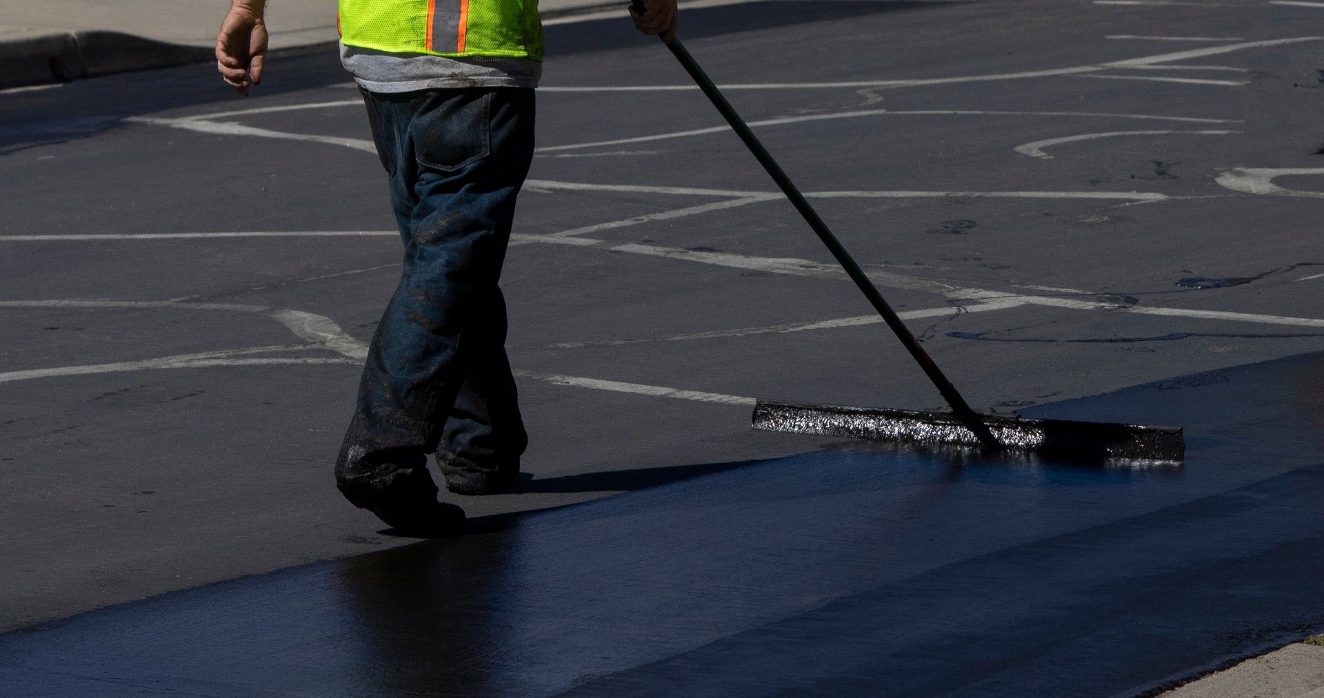 A man is walking down a street with a broom.