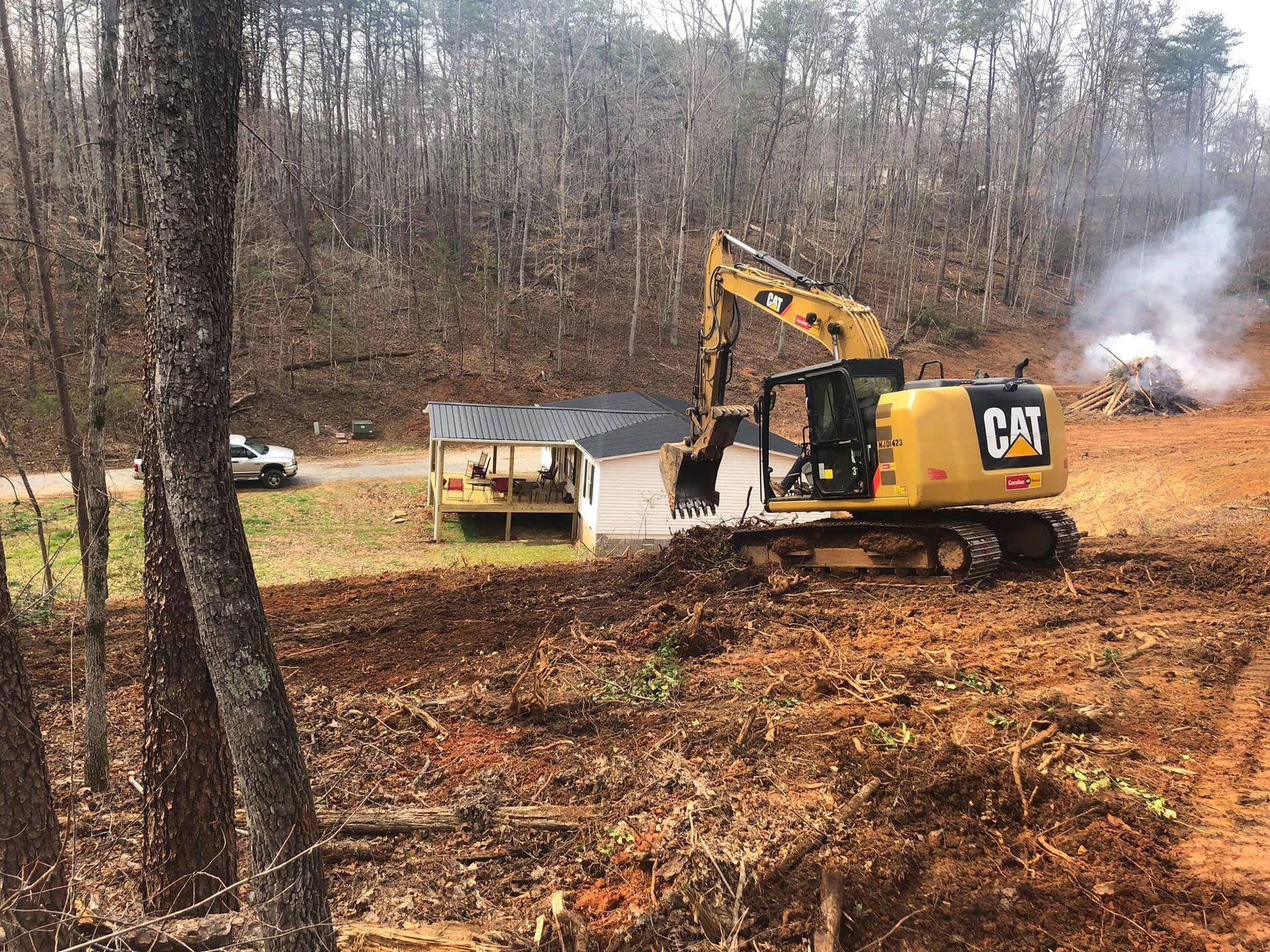 A cat excavator is moving dirt in a field.