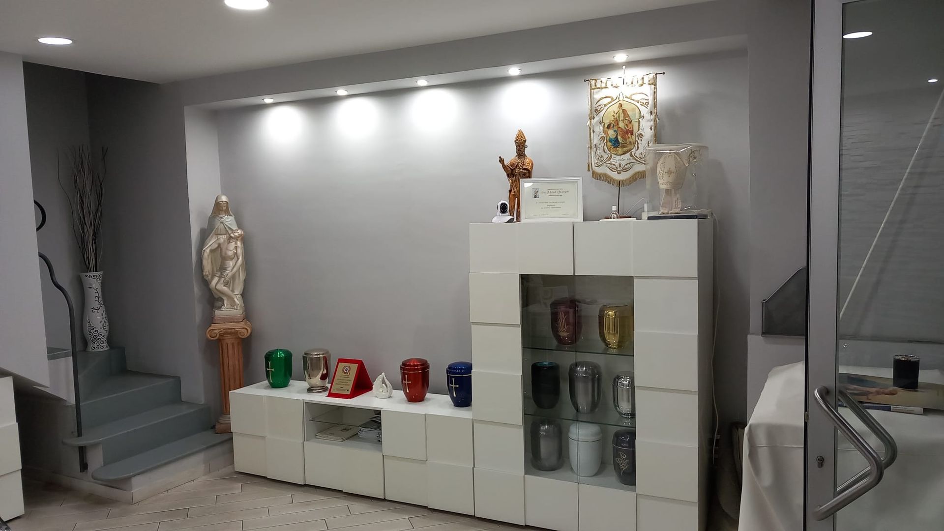 Un soggiorno con una vetrina piena di urne e una statua di Gesù.